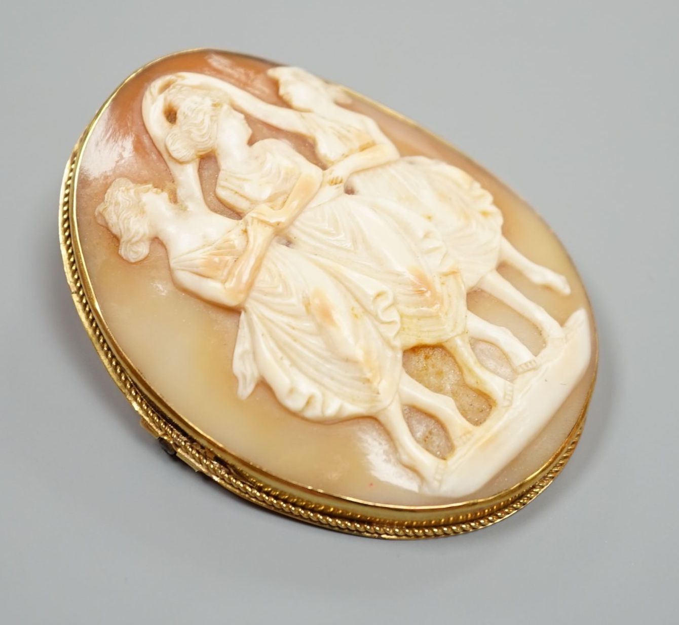 A yellow metal mounted oval cameo shell pendant brooch, carved with The Three Graces, 62mm, gross weight 21.4 grams.